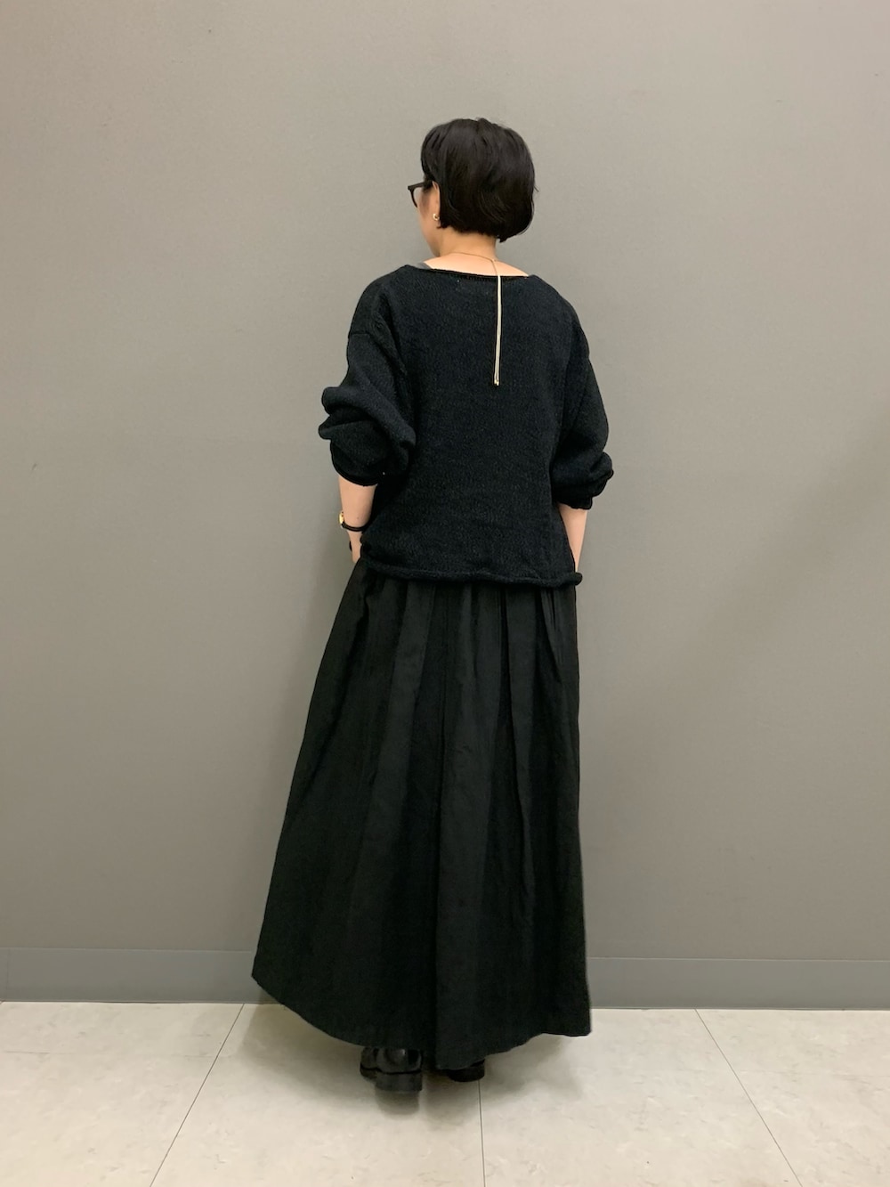 ブラック系のスカート、ブラック系のニット/セーター、ブラック系のブーツを着用したレディースの秋コーディネートの5枚目の写真