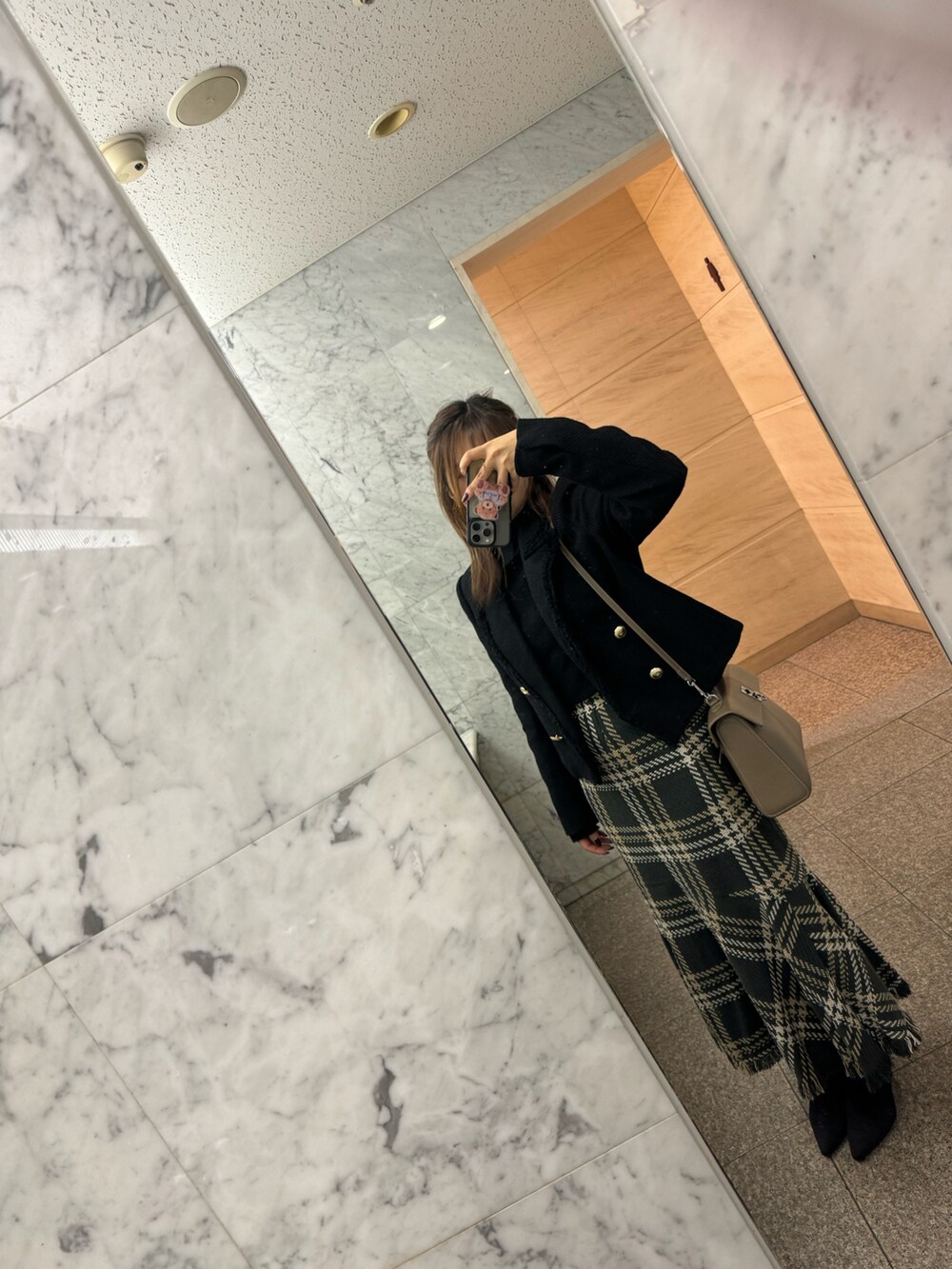 グリーン系のスカート、ブラック系のブーツ、ブラック系のジャケット/アウターを着用したレディースの秋コーディネートの2枚目の写真