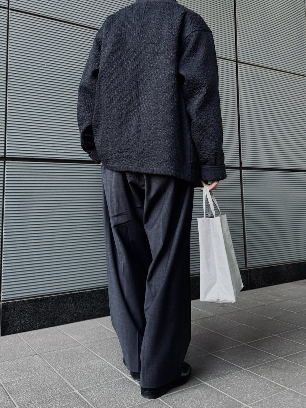 グレー系のノーカラージャケット、グレー系のスラックス、ブラック系のドレスシューズを着用したメンズの春コーディネートの3枚目の写真