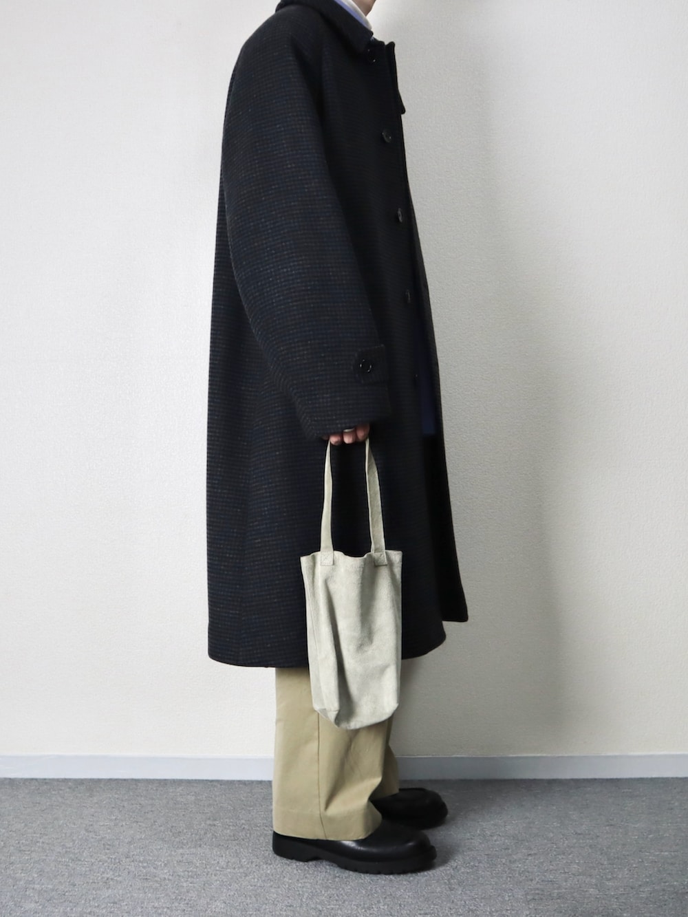 グレー系のトートバッグ、グレー系のステンカラーコート、ブラック系のドレスシューズを着用したメンズの秋コーディネートの2枚目の写真