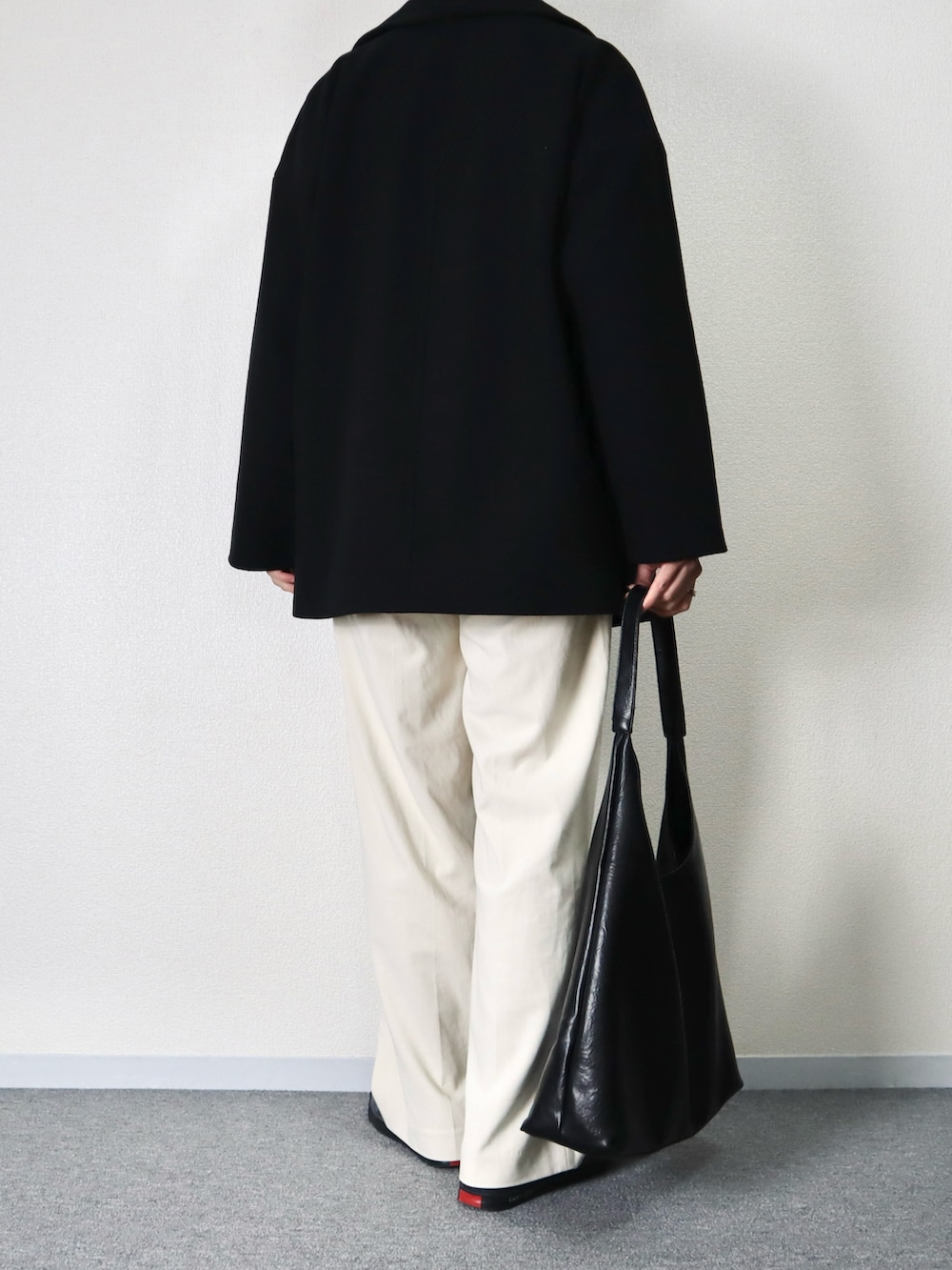 ブラック系のジャケット/アウター、オレンジ系のニット/セーター、ホワイト系のパンツを着用したメンズの冬コーディネートの3枚目の写真