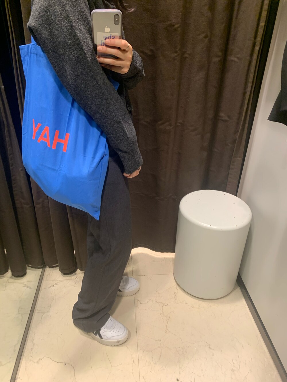 ブルー系のトートバッグ、グレー系のスラックス、ホワイト系のスニーカーを着用したレディースの冬コーディネートの2枚目の写真