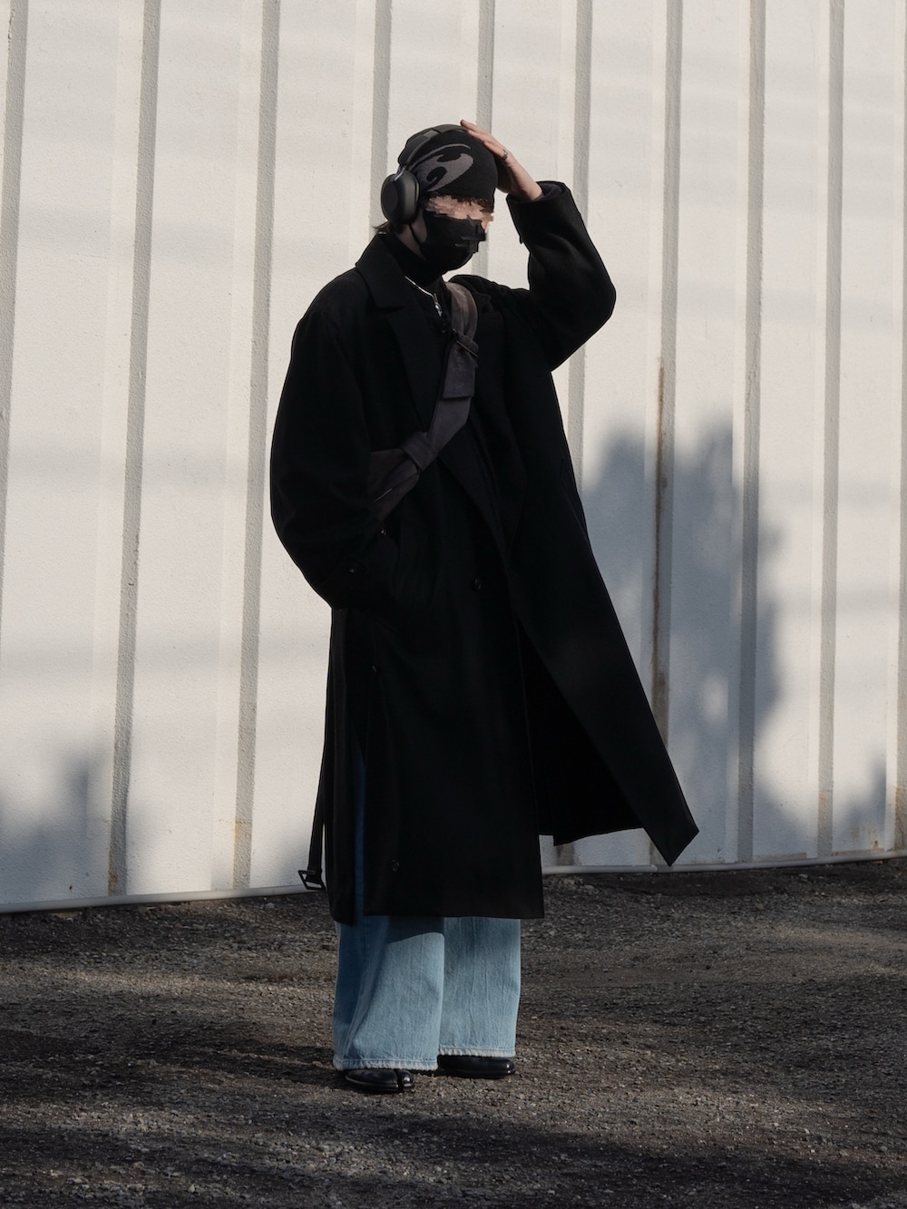 ブラック系のステンカラーコート、ブルー系のデニムパンツ、ブラック系のブーツを着用したメンズの冬コーディネートの2枚目の写真