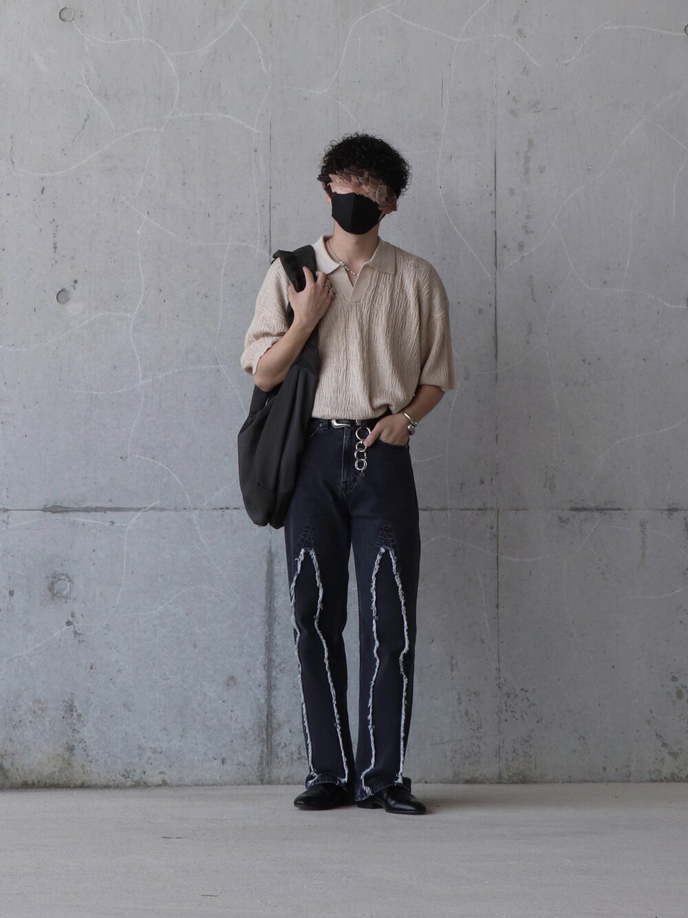 ベージュ系のトップス、ブラック系のデニムパンツ、ブルー系のトップスを着用したメンズの春コーディネートの3枚目の写真