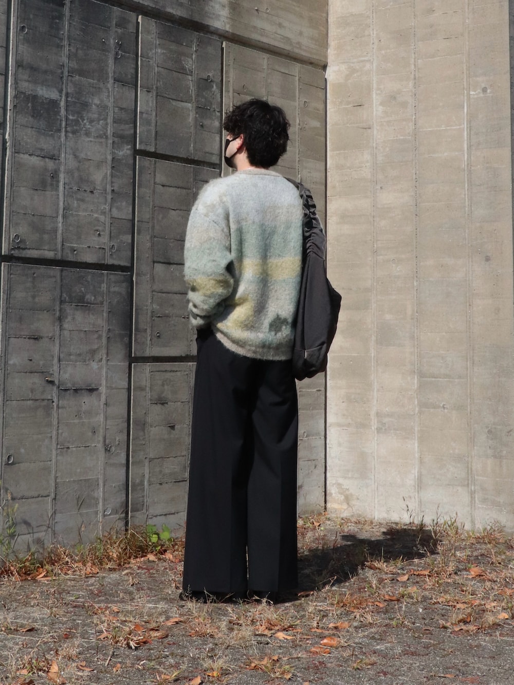 ホワイト系のニット/セーター、ブラック系のショルダーバッグ、ブラック系のスラックスを着用したメンズの秋コーディネートの3枚目の写真