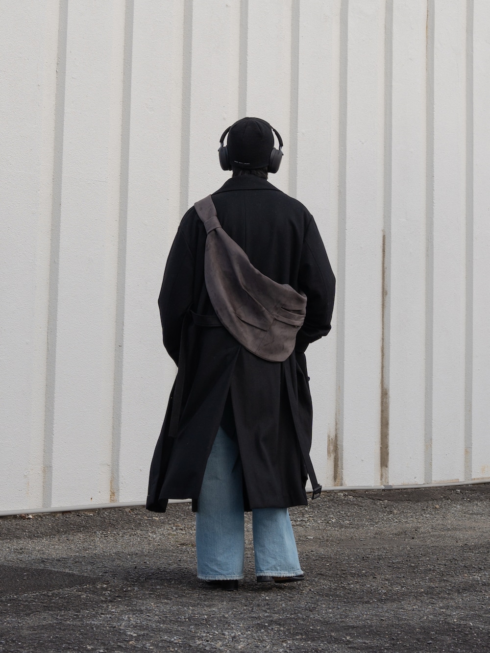 ブラック系のステンカラーコート、ブルー系のデニムパンツ、ブラック系のブーツを着用したメンズの冬コーディネートの3枚目の写真