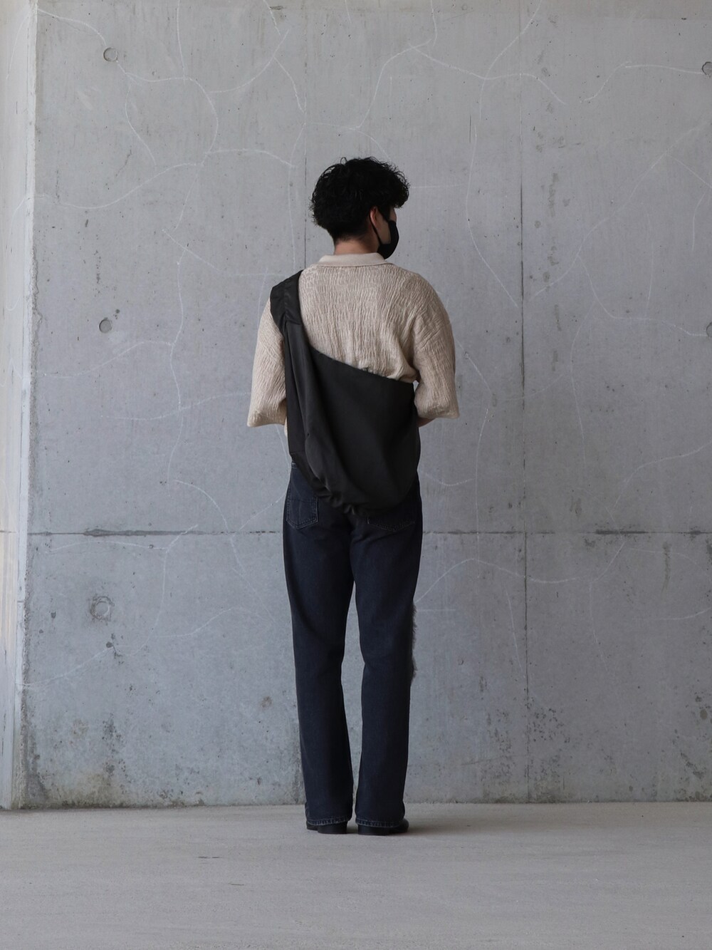 ベージュ系のトップス、ブラック系のデニムパンツ、ブルー系のトップスを着用したメンズの春コーディネートの2枚目の写真