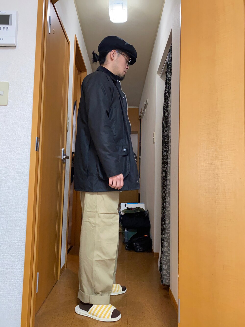 ブラック系のその他アウター、グレー系のカーディガン/ボレロ、ベージュ系のチノパンツを着用したメンズの冬コーディネートの2枚目の写真