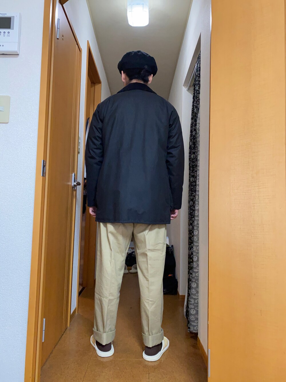 ブラック系のその他アウター、グレー系のカーディガン/ボレロ、ベージュ系のチノパンツを着用したメンズの冬コーディネートの3枚目の写真