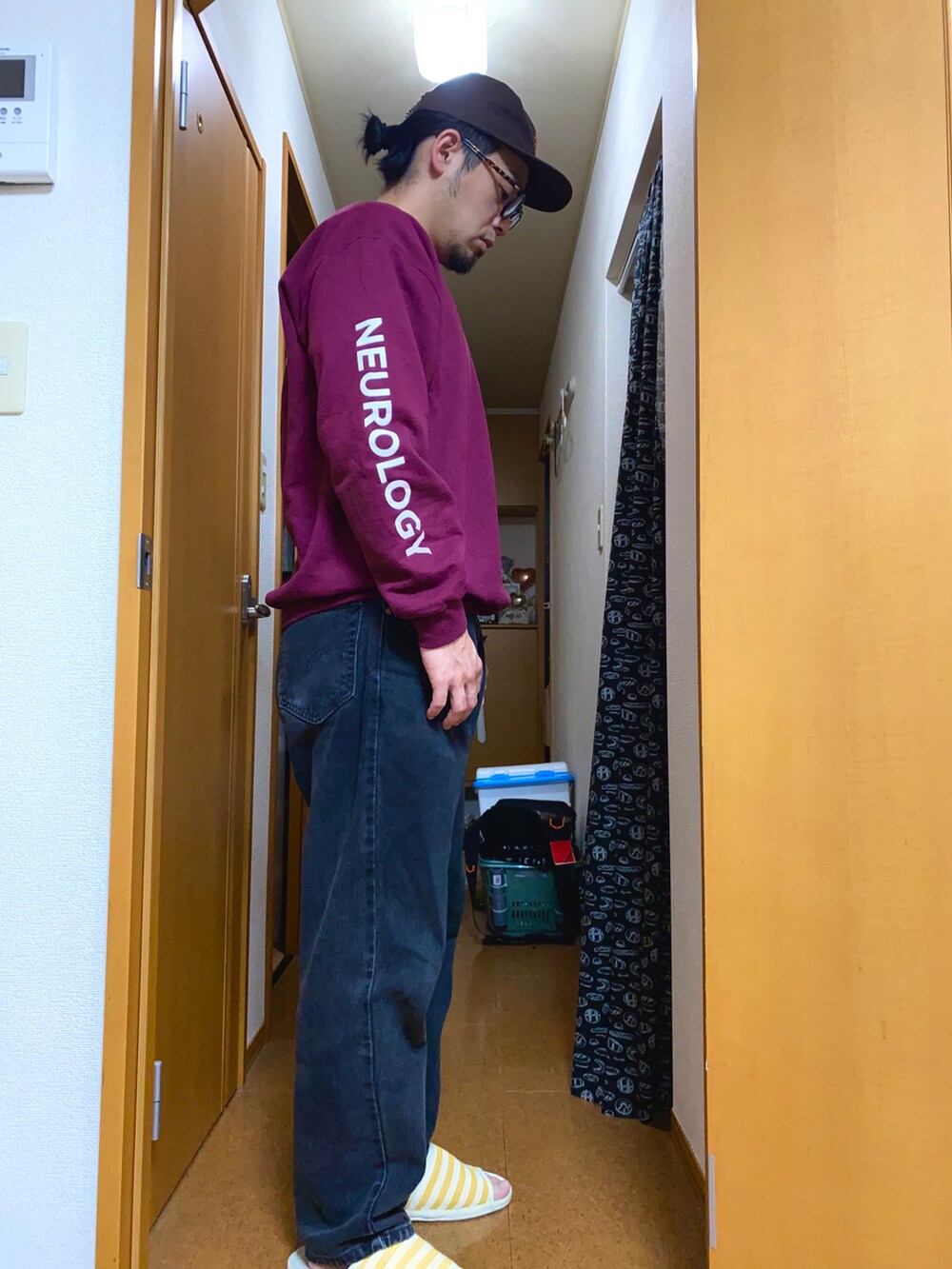 レッド系のスウェット、ブラック系のデニムパンツ、ブラウン系のキャップを着用したメンズの春コーディネートの2枚目の写真