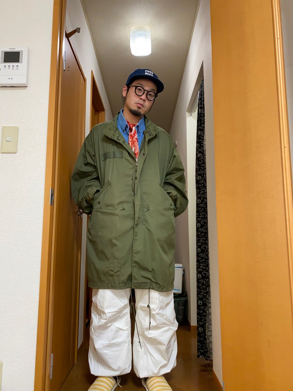グリーン系のミリタリージャケット、ブルー系のシャツ/ブラウス、ホワイト系のパンツを着用したメンズの冬コーディネートの2枚目の写真