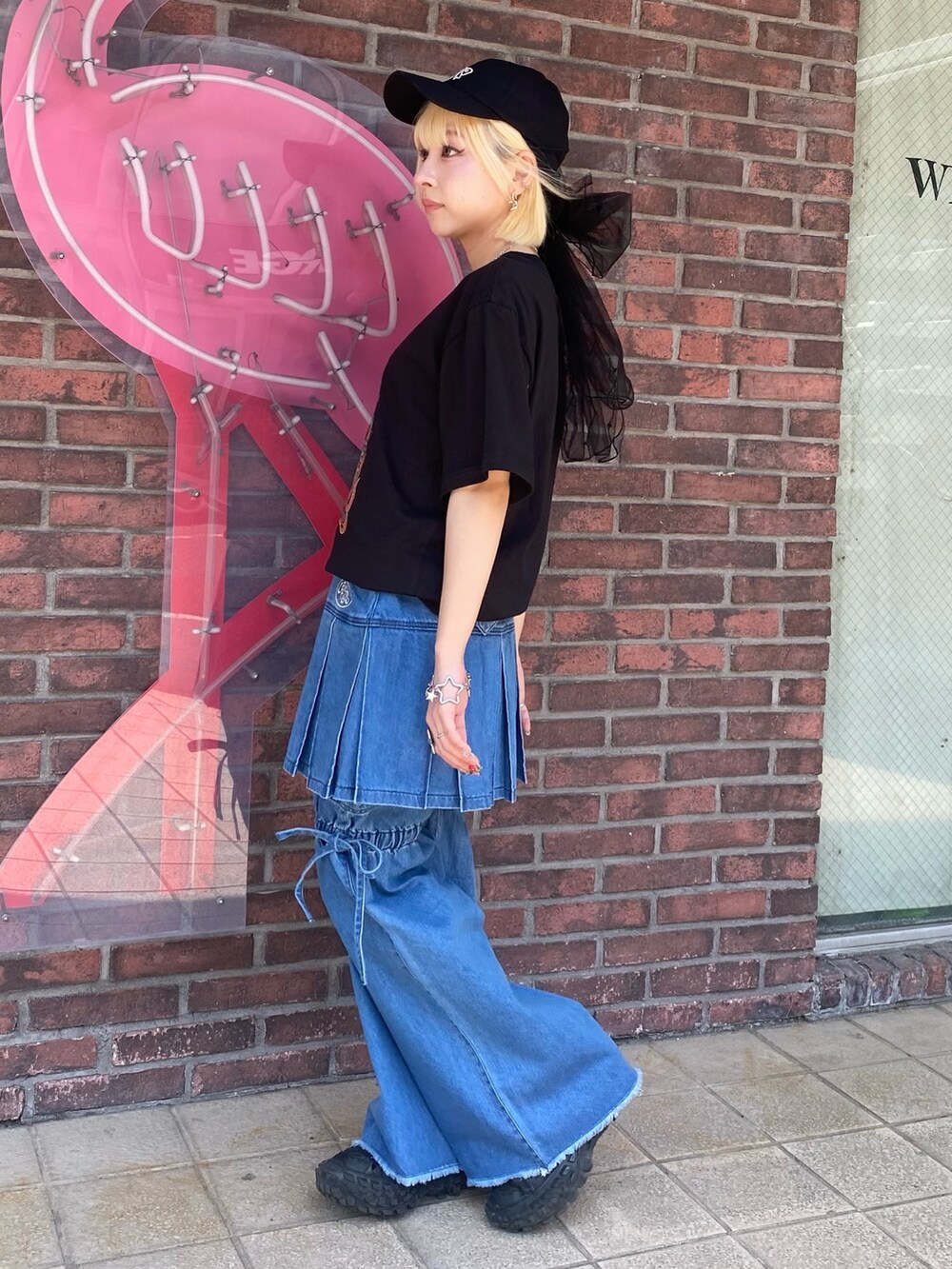 ブルー系のスカート、ブラック系のTシャツ/カットソー、ブラック系のキャップを着用したレディースの春コーディネートの4枚目の写真