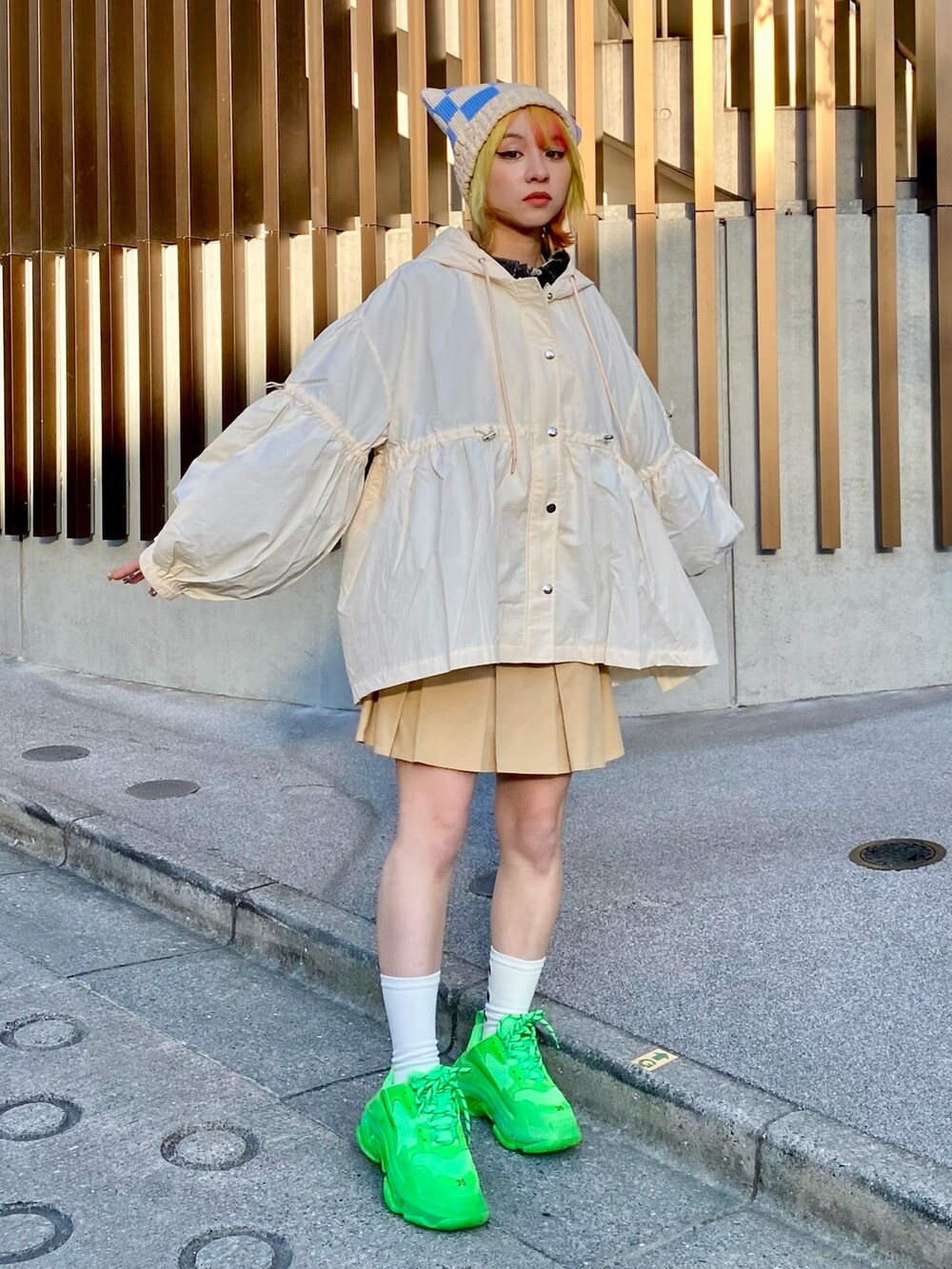 ベージュ系のナイロンジャケット、ブラック系のポロシャツ、ベージュ系のスカートを着用したレディースの春コーディネートの2枚目の写真