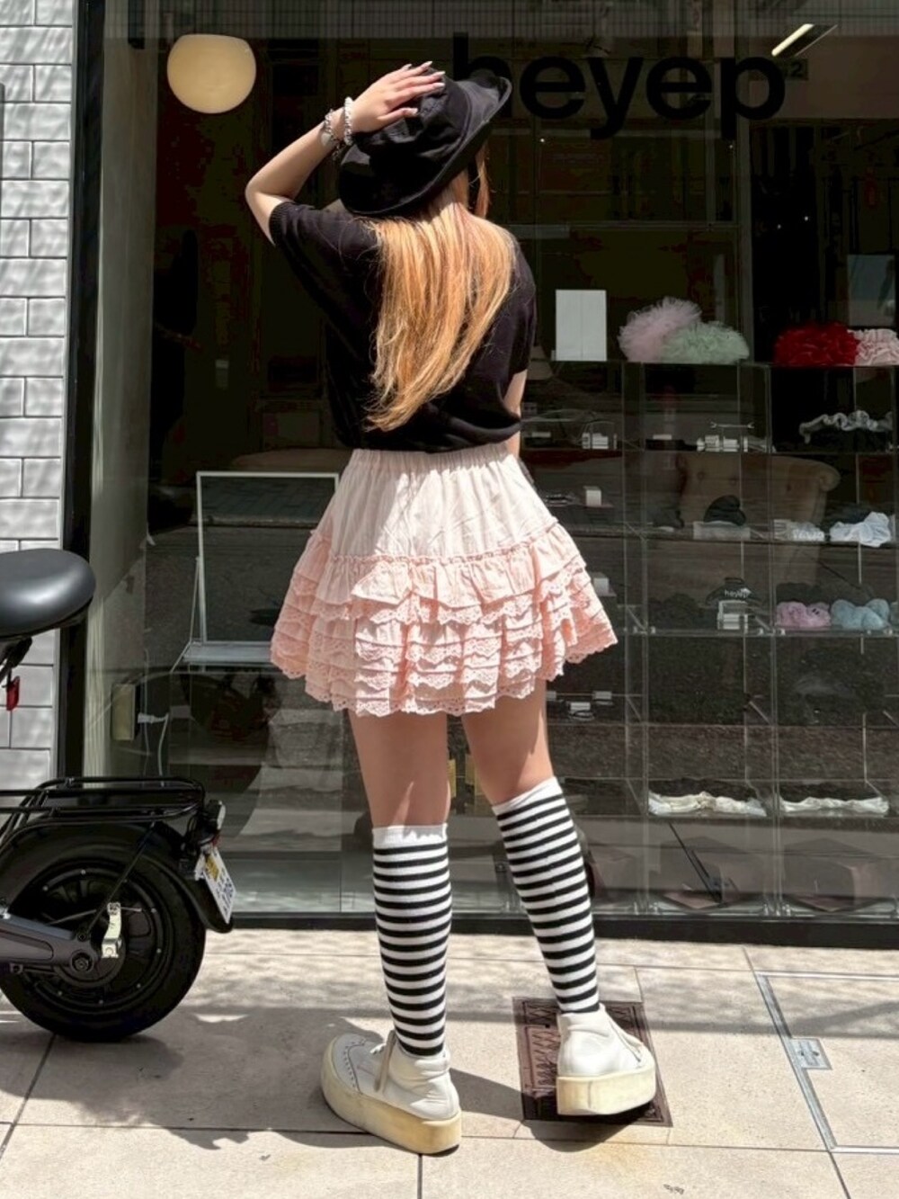 ピンク系のスカート、ブラック系のニット/セーター、ブラック系のハットを着用したレディースの夏コーディネートの4枚目の写真