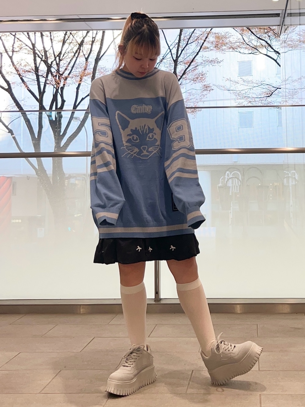 ブラック系のスカート、ブルー系のニット/セーター、ブラック系のダウンジャケット/コートを着用したレディースの冬コーディネートの6枚目の写真