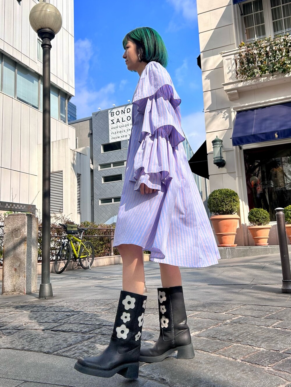 ベージュ系のトレンチコート、ブルー系のワンピース、ブラック系のブーツを着用したレディースの冬コーディネートの4枚目の写真