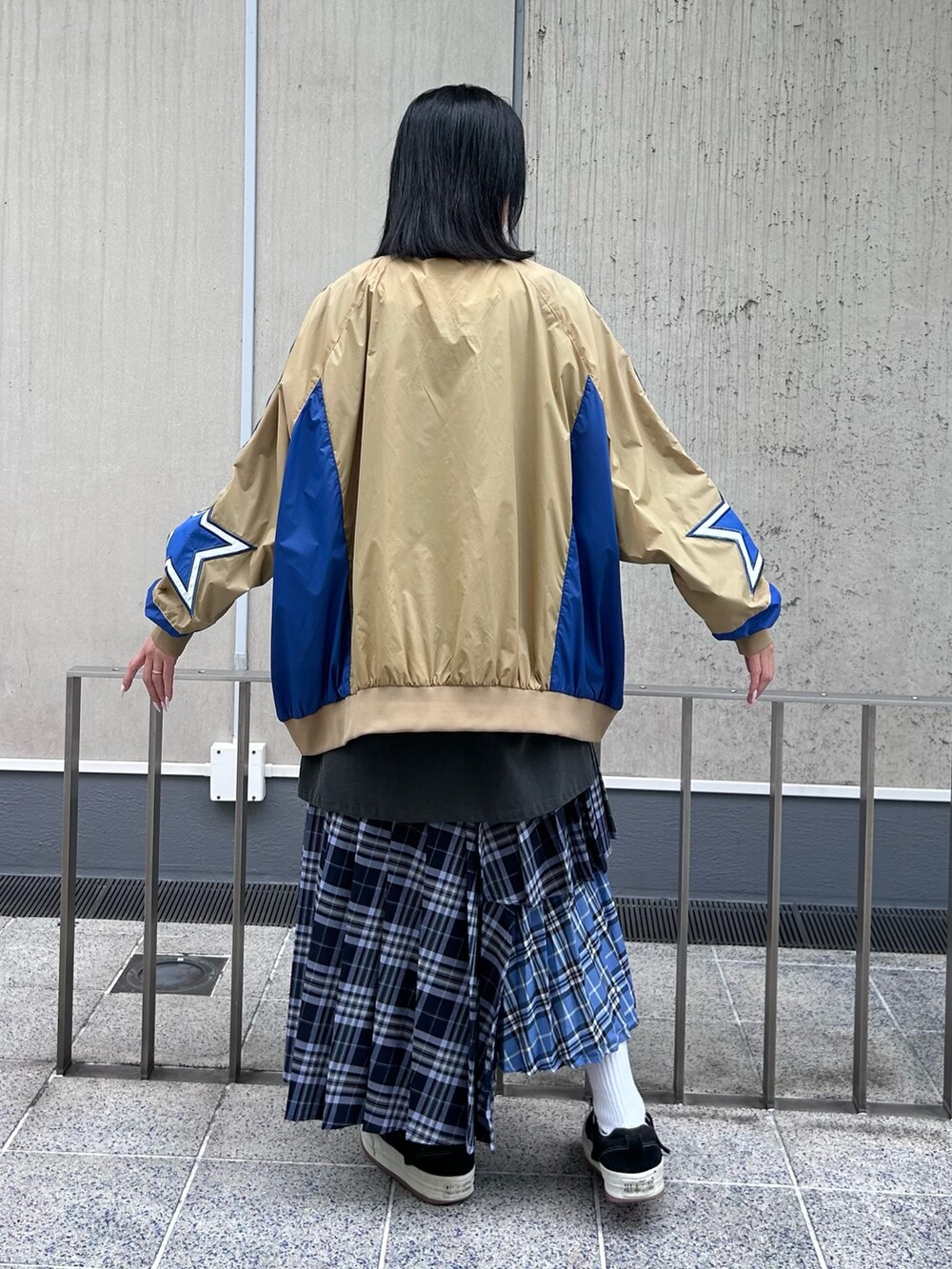 ブルー系のスカート、グレー系のTシャツ/カットソー、ベージュ系のナイロンジャケットを着用したレディースの秋コーディネートの6枚目の写真