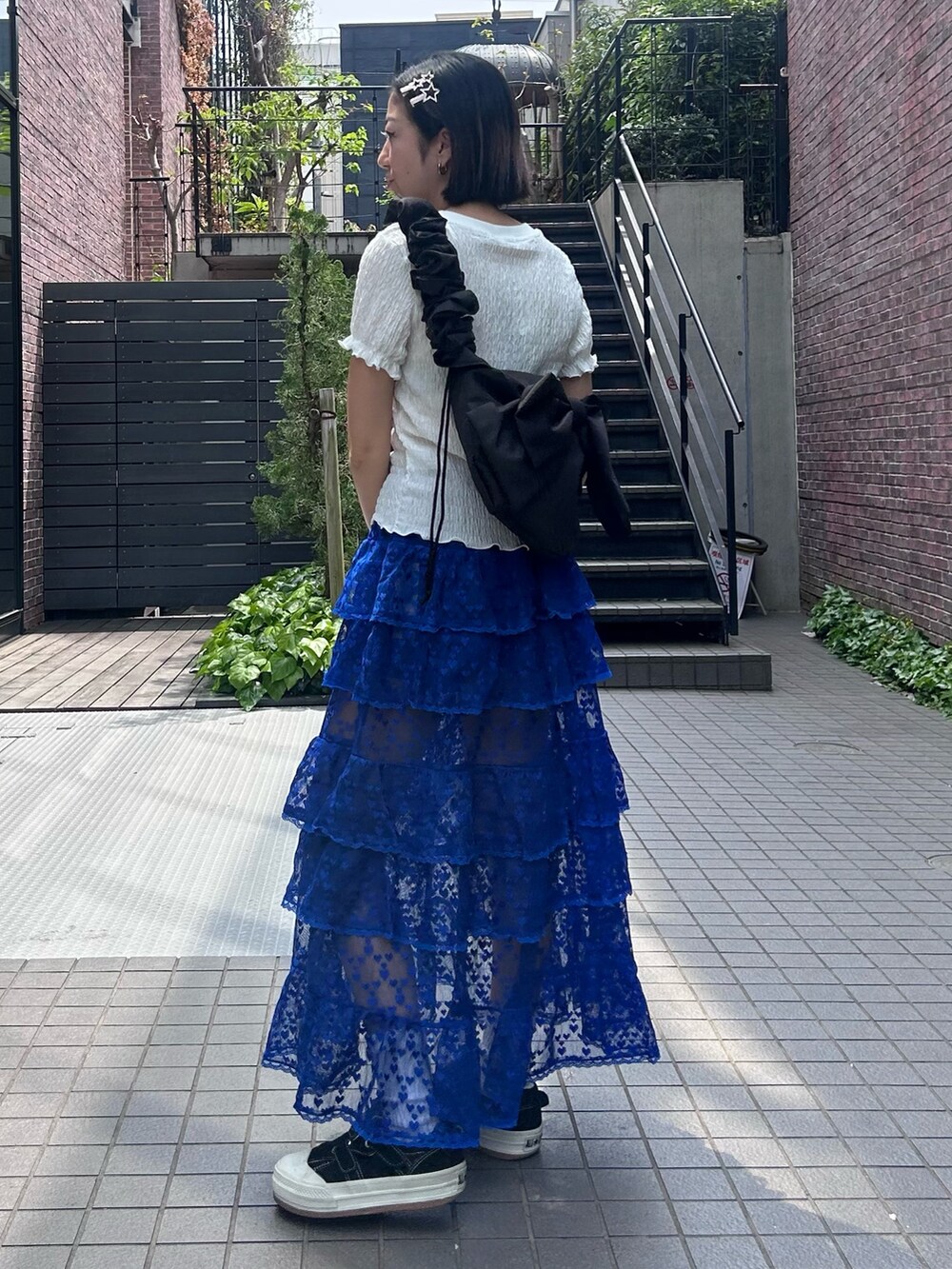 ブラック系のショルダーバッグ、ブルー系のスカート、ホワイト系のTシャツ/カットソーを着用したレディースの春コーディネートの5枚目の写真