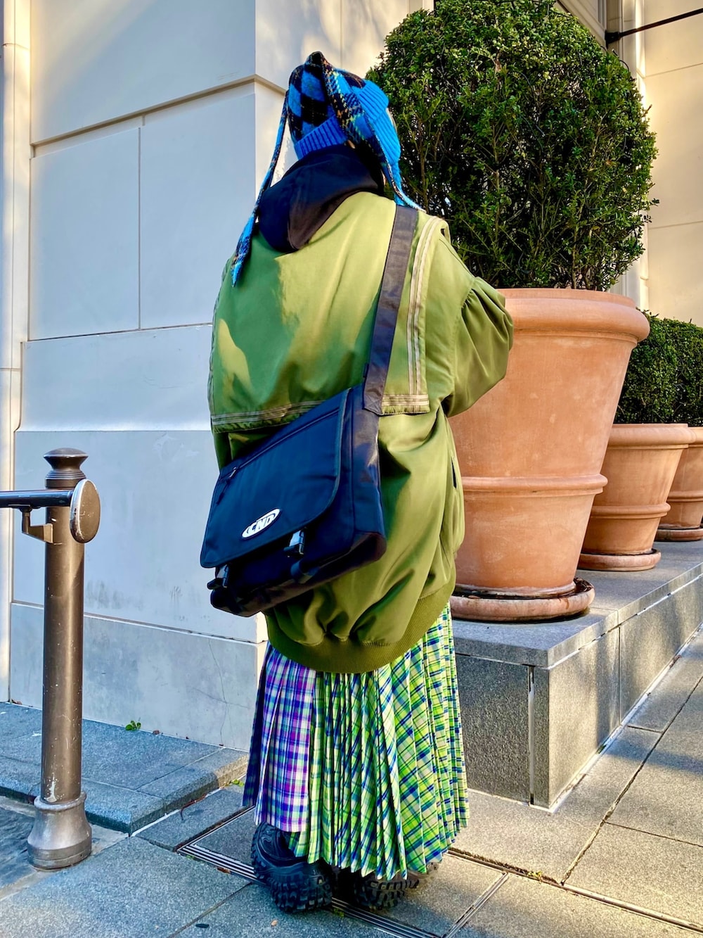 パープル系のスカート、グリーン系のMA-1、ブラック系のパーカーを着用したレディースの冬コーディネートの4枚目の写真