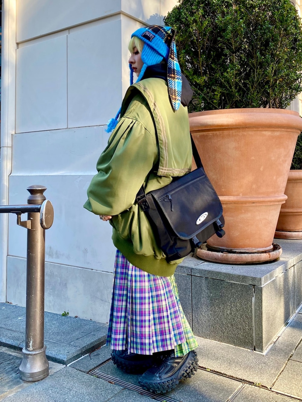 パープル系のスカート、グリーン系のMA-1、ブラック系のパーカーを着用したレディースの冬コーディネートの3枚目の写真