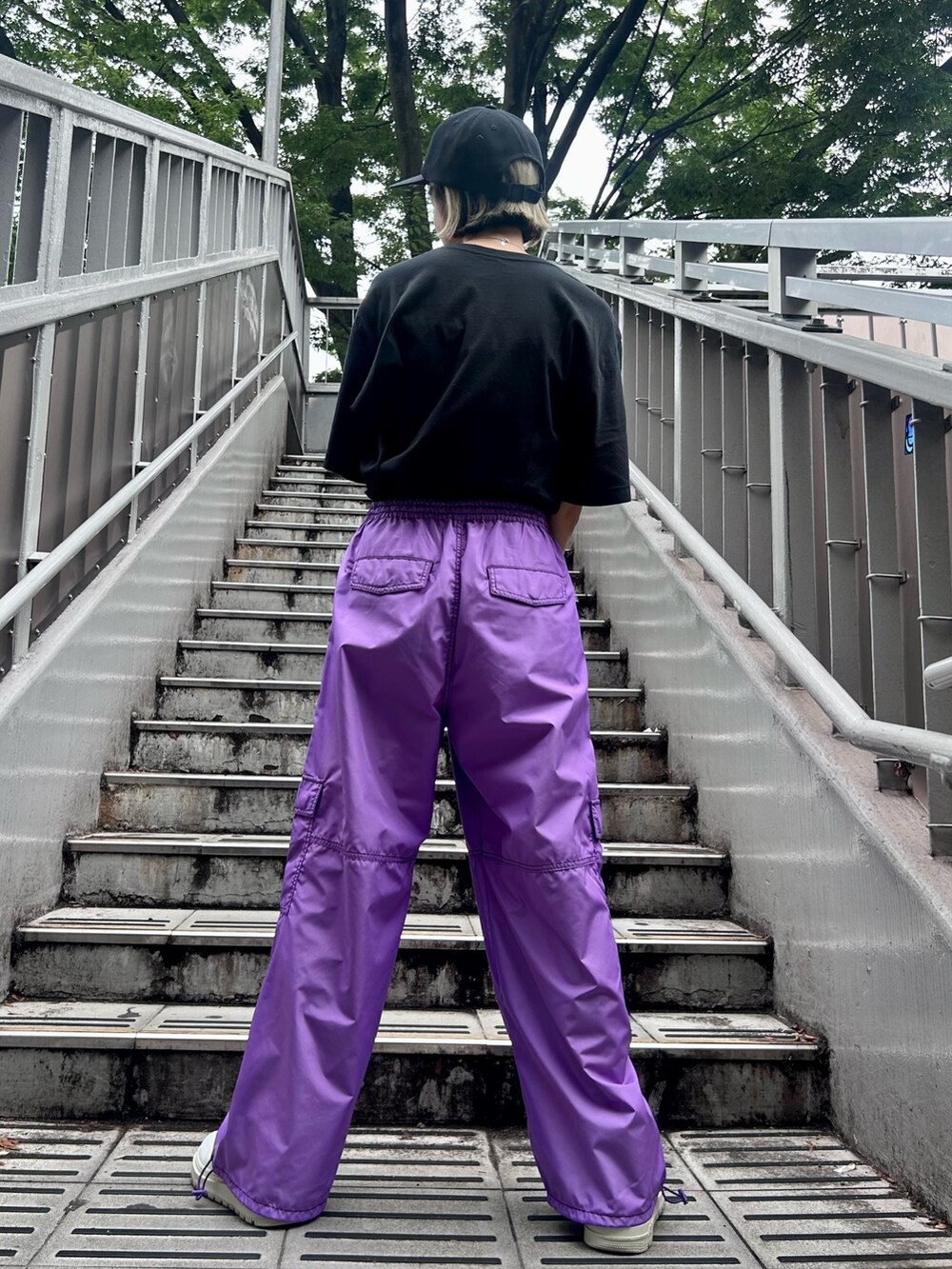 パープル系のカーゴパンツ、ブラック系のTシャツ/カットソー、ブラック系のキャップを着用したレディースの夏コーディネートの4枚目の写真