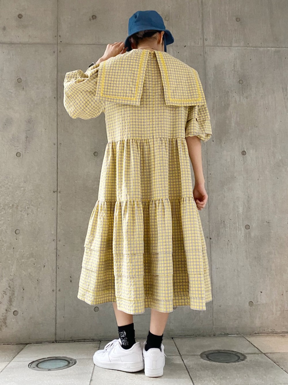 イエロー系のワンピース、ホワイト系のスニーカーを着用したレディースの春コーディネートの2枚目の写真