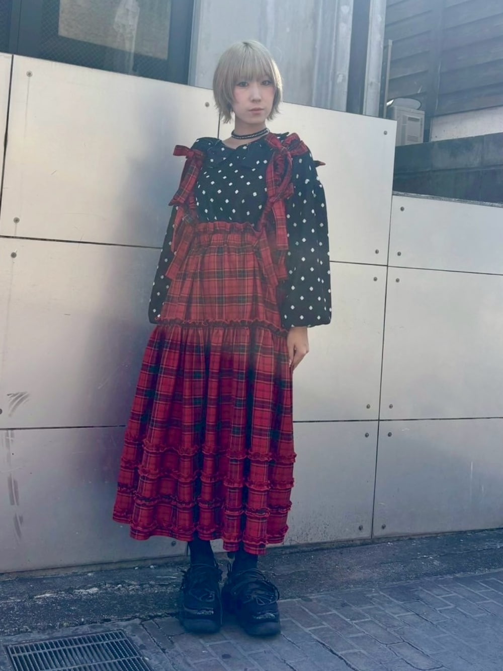 レッド系のジャンパースカート、ブラック系のニット/セーター、ブラック系のテーラードジャケットを着用したレディースの秋コーディネートの4枚目の写真