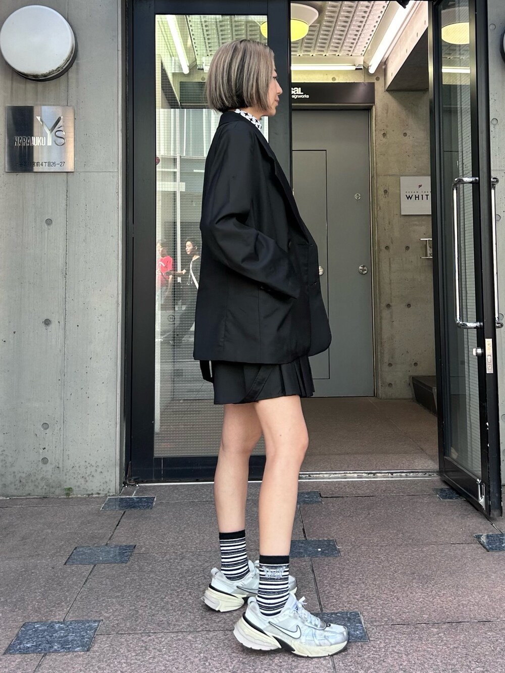 ブラック系のテーラードジャケット、ホワイト系のその他トップス、ブラック系のスカートを着用したレディースの秋コーディネートの4枚目の写真