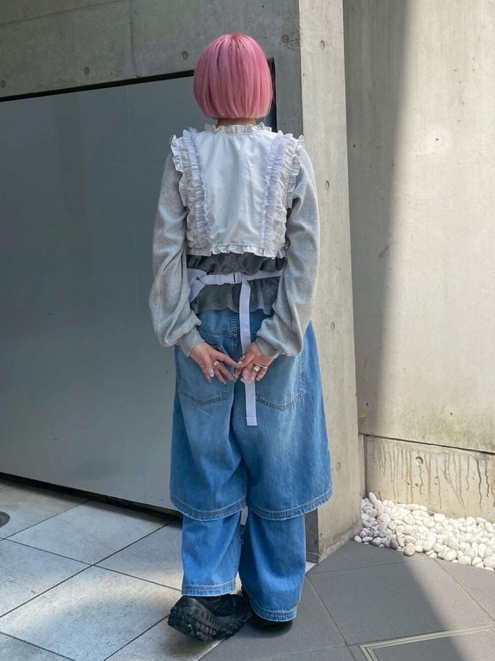 ブルー系のデニムパンツ、ホワイト系のボディバッグ/ウエストポーチ、グレー系のベストを着用したレディースの秋コーディネートの4枚目の写真