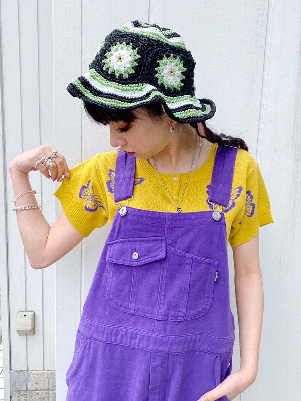 パープル系のサロペット/オーバーオール、イエロー系のカーディガン/ボレロ、ブラック系のハットを着用したレディースの春コーディネートの2枚目の写真