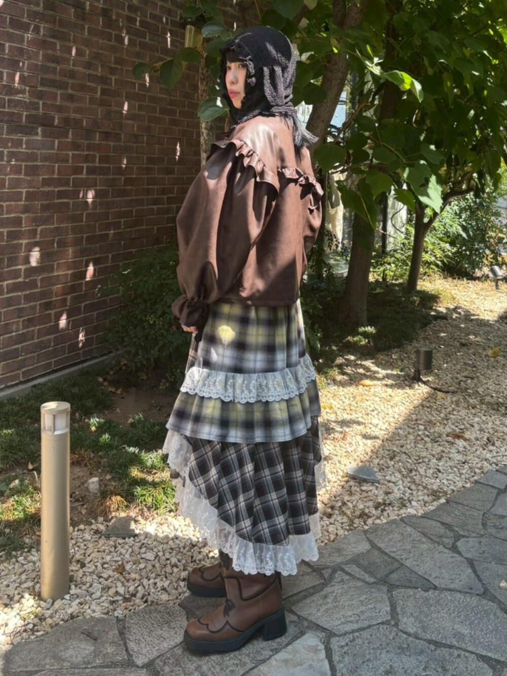 ブラウン系のライダースジャケット、イエロー系のスカート、ブラウン系のブーツを着用したレディースの冬コーディネートの2枚目の写真