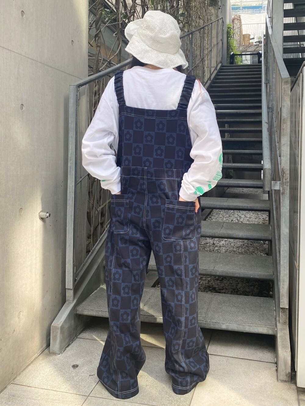 ホワイト系のTシャツ/カットソー、ブルー系のサロペット/オーバーオール、ホワイト系のハットを着用したレディースの春コーディネートの4枚目の写真