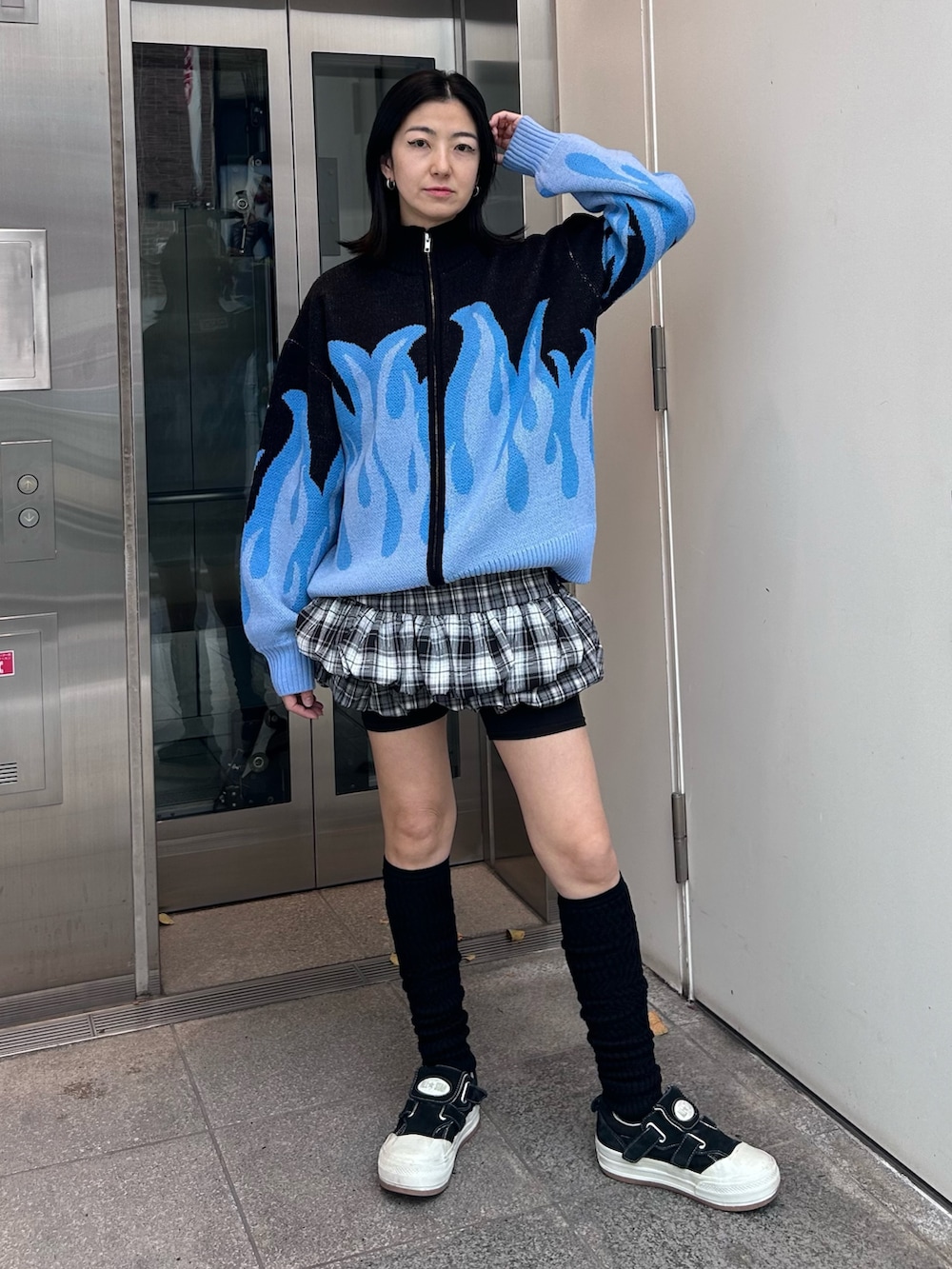 グレー系のスカート、ブラック系のニット/セーター、ブラック系のソックス/靴下を着用したレディースの秋コーディネートの2枚目の写真