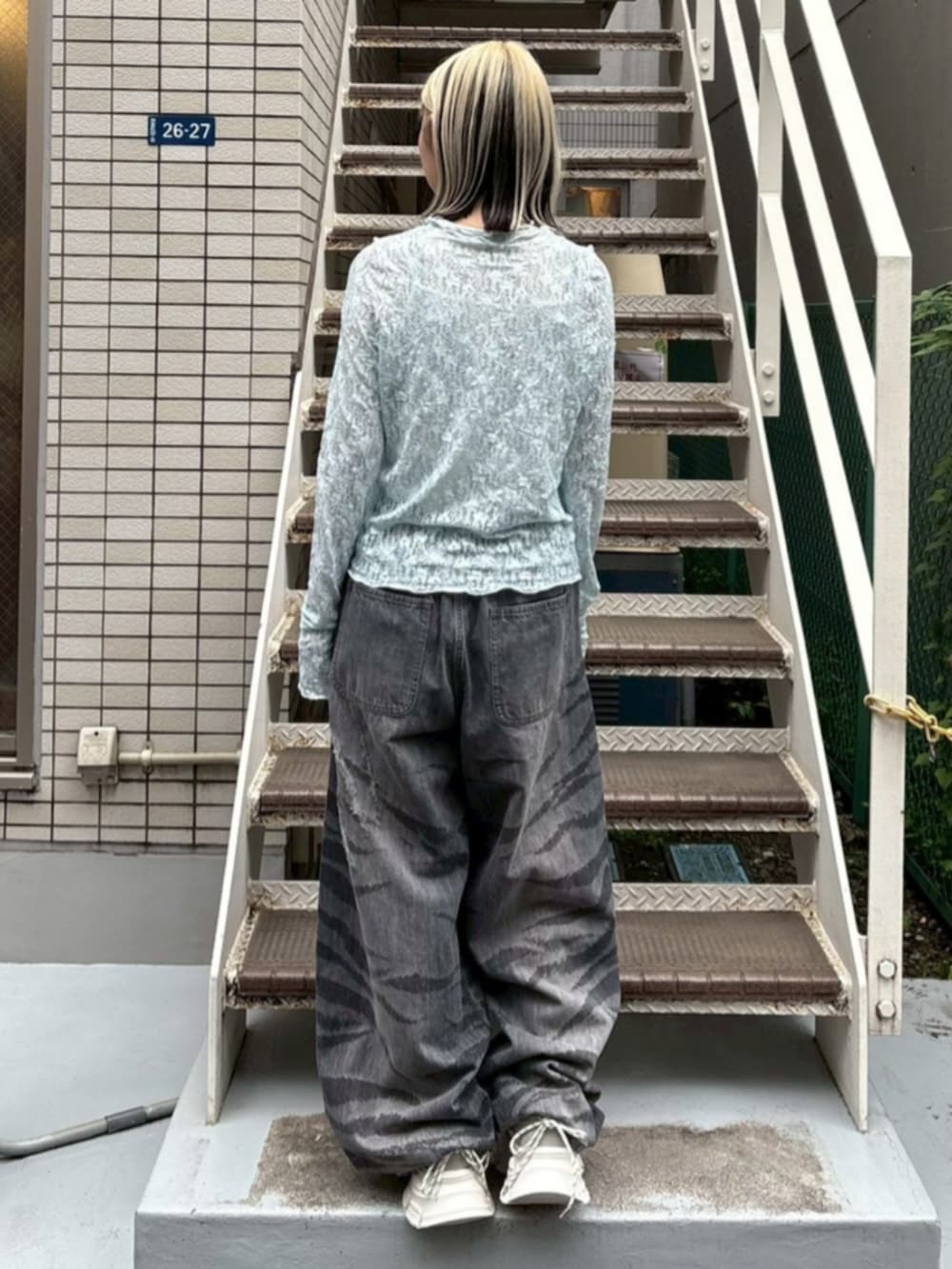 ブラック系のデニムパンツ、ブルー系のTシャツ/カットソー、ホワイト系のスニーカーを着用したレディースの夏コーディネートの2枚目の写真