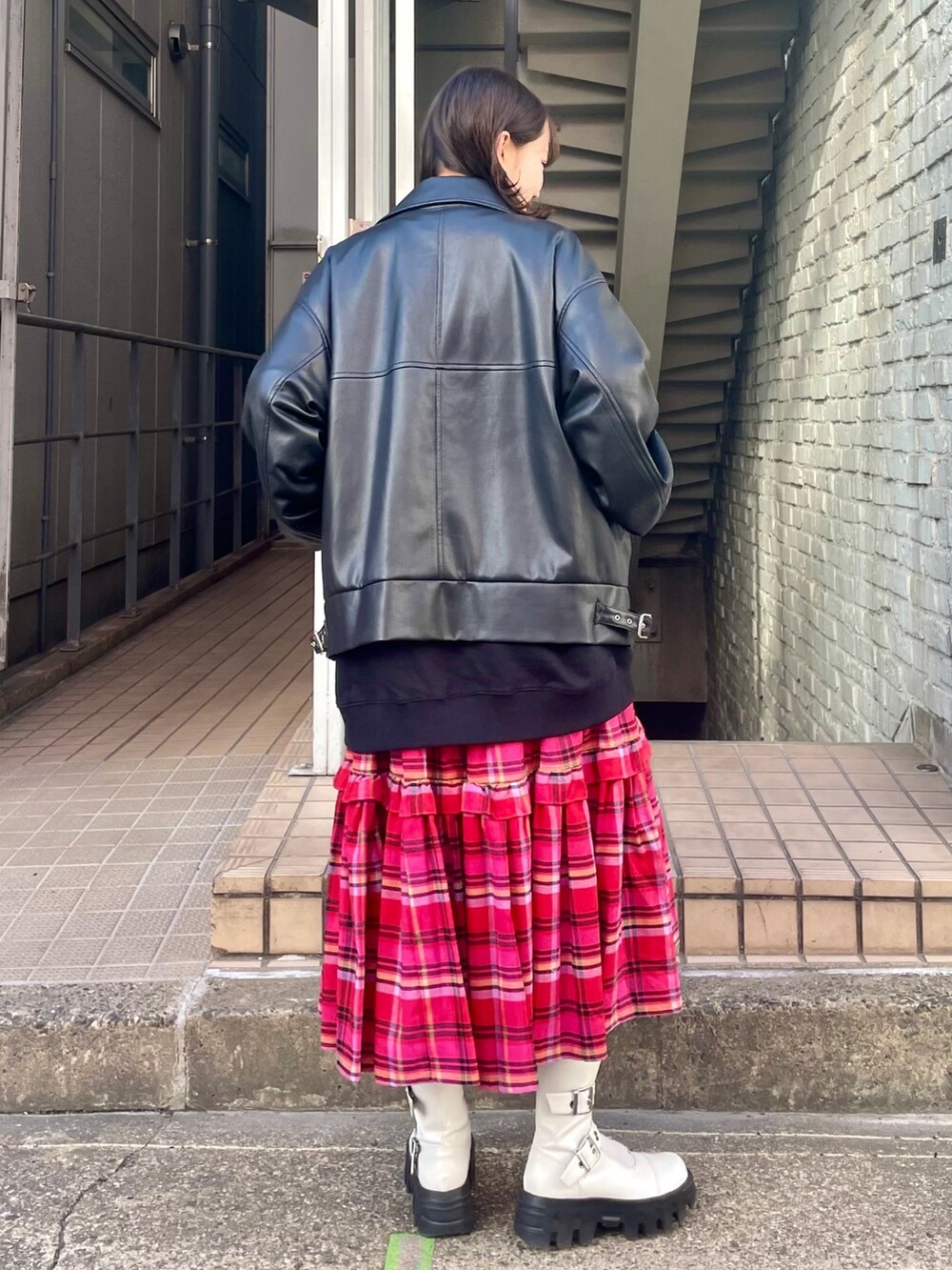 ブラック系のライダースジャケット、ホワイト系のブーツ、ピンク系のスカートを着用したレディースの秋コーディネートの4枚目の写真