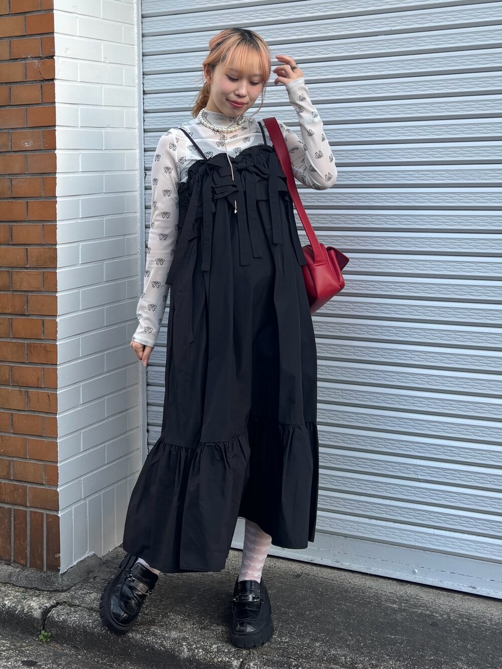 ブラック系のワンピース、ホワイト系のその他トップス、レッド系のショルダーバッグを着用したレディースの春コーディネートの2枚目の写真