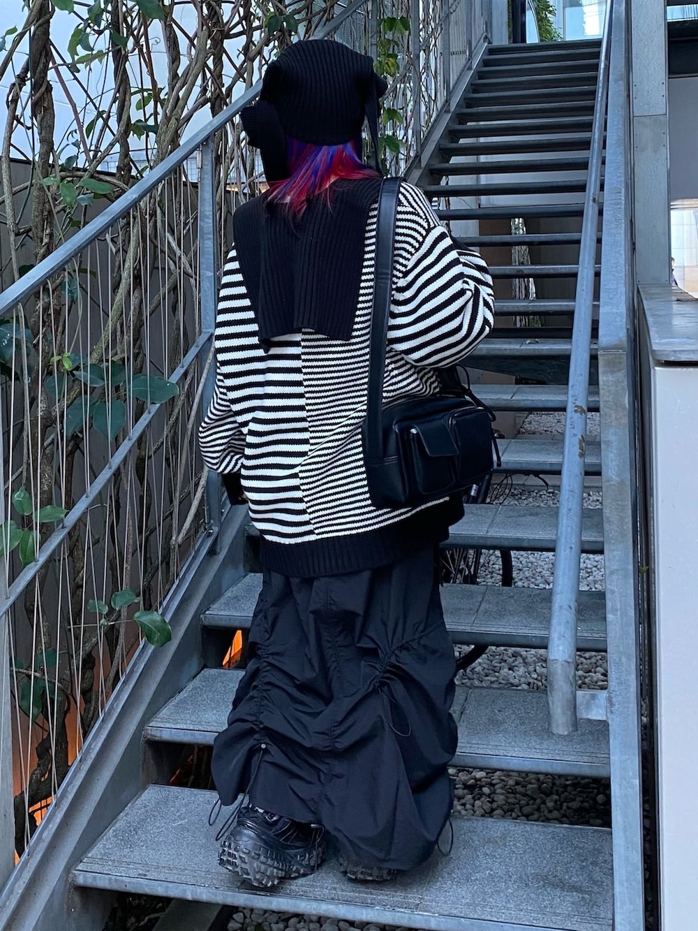 ブラック系のスカート、ブラック系のショルダーバッグ、ブラック系のニット/セーターを着用したレディースの冬コーディネートの5枚目の写真