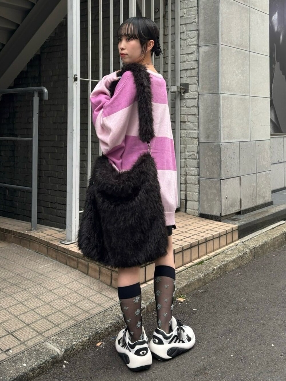 ブラック系のショルダーバッグ、ブラック系のスカート、ピンク系のニット/セーターを着用したレディースの秋コーディネートの3枚目の写真