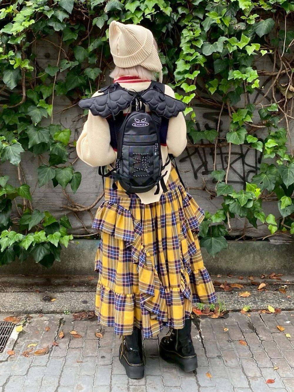 ブラック系のバックパック/リュック、イエロー系のスカート、ホワイト系のニット/セーターを着用したレディースの秋コーディネートの5枚目の写真