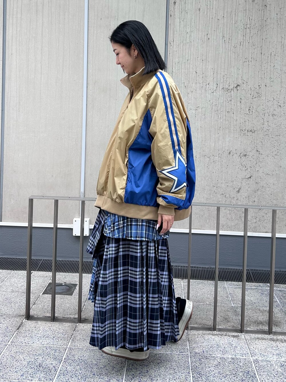 ブルー系のスカート、グレー系のTシャツ/カットソー、ベージュ系のナイロンジャケットを着用したレディースの秋コーディネートの5枚目の写真