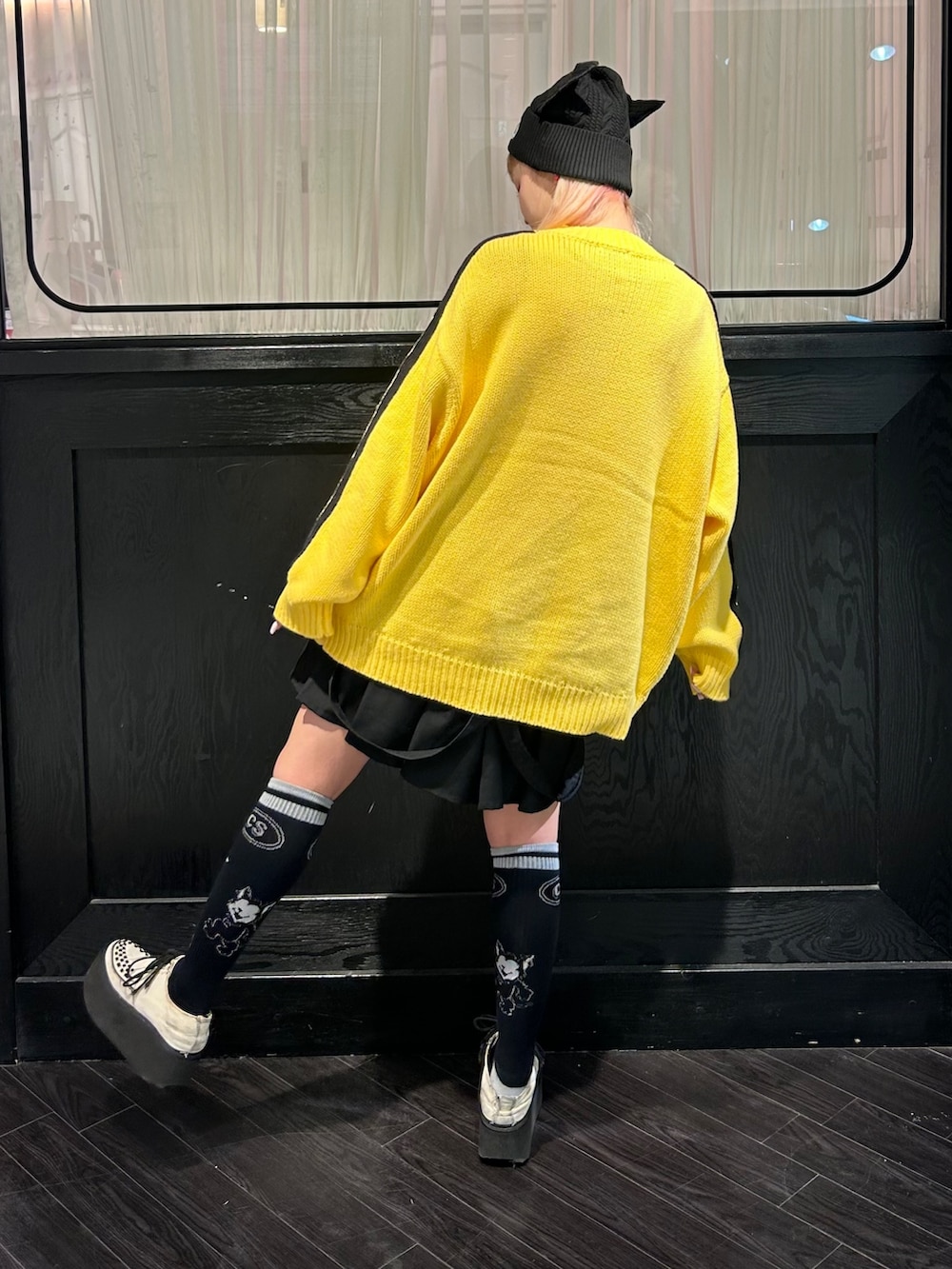 イエロー系のニット/セーター、ブラック系のスカート、ブラック系のニットキャップ/ビーニーを着用したレディースの秋コーディネートの5枚目の写真