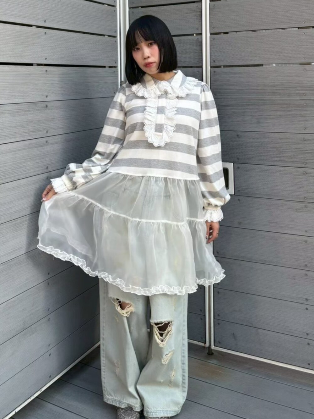 グレー系のワンピース、ブルー系のデニムパンツを着用したレディースの春コーディネートの2枚目の写真