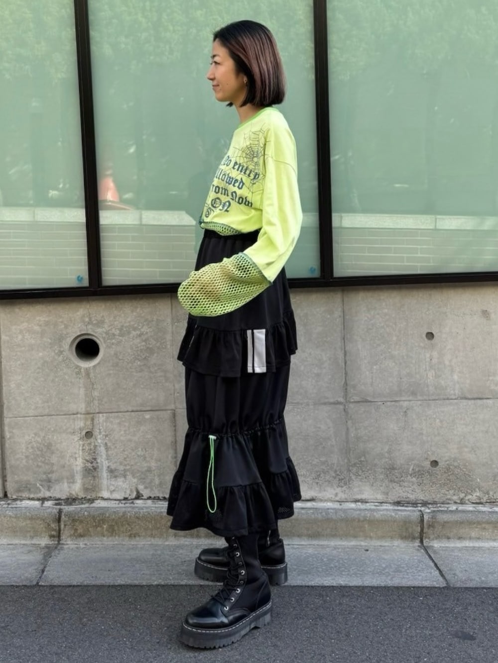 グリーン系のTシャツ/カットソー、ブラック系のスカートを着用したレディースの春コーディネートの4枚目の写真