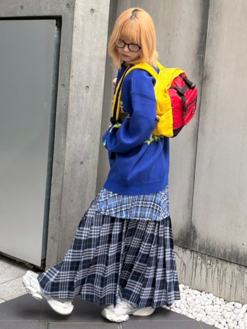 レッド系のバックパック/リュック、ブルー系のスカート、ブルー系のニット/セーターを着用したレディースの秋コーディネートの5枚目の写真