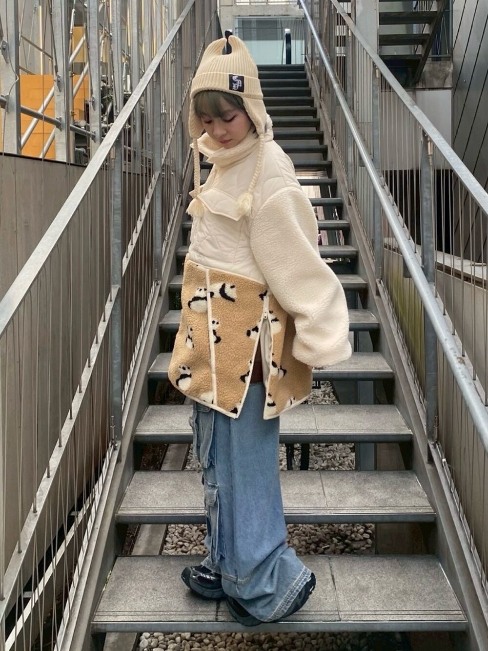 ホワイト系のダウンジャケット/コート、ブルー系のデニムパンツ、ホワイト系のニットキャップ/ビーニーを着用したレディースの秋コーディネートの2枚目の写真