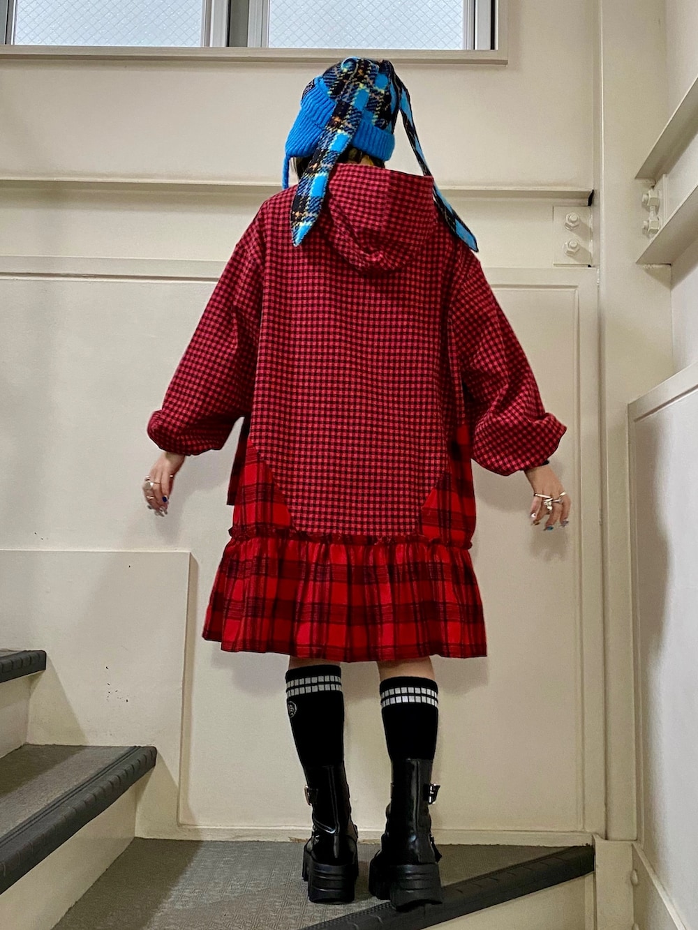 レッド系のワンピース、ブラック系のブーツ、ブルー系のニットキャップ/ビーニーを着用したレディースの秋コーディネートの4枚目の写真