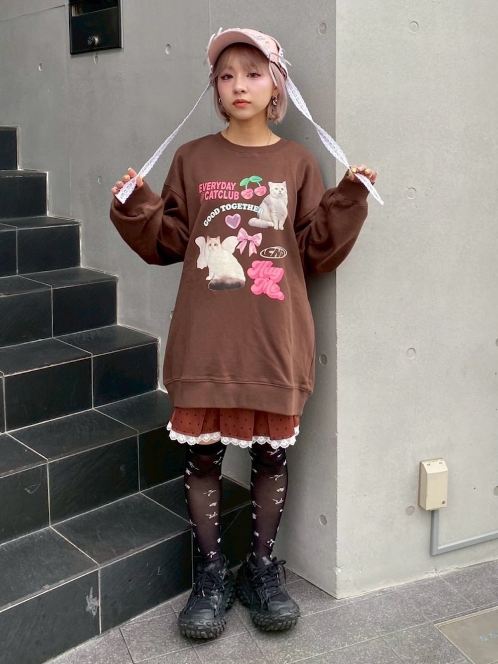 ブラウン系のスウェット、ブラウン系のスカート、ピンク系のキャップを着用したレディースの秋コーディネートの2枚目の写真