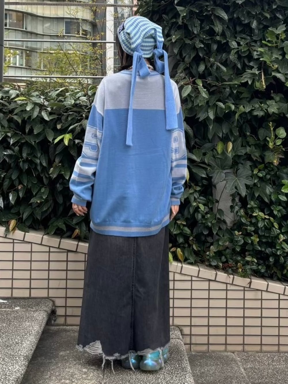 ブラック系のデニムスカート、ブルー系のニット/セーター、グリーン系のニットキャップ/ビーニーを着用したレディースの冬コーディネートの5枚目の写真