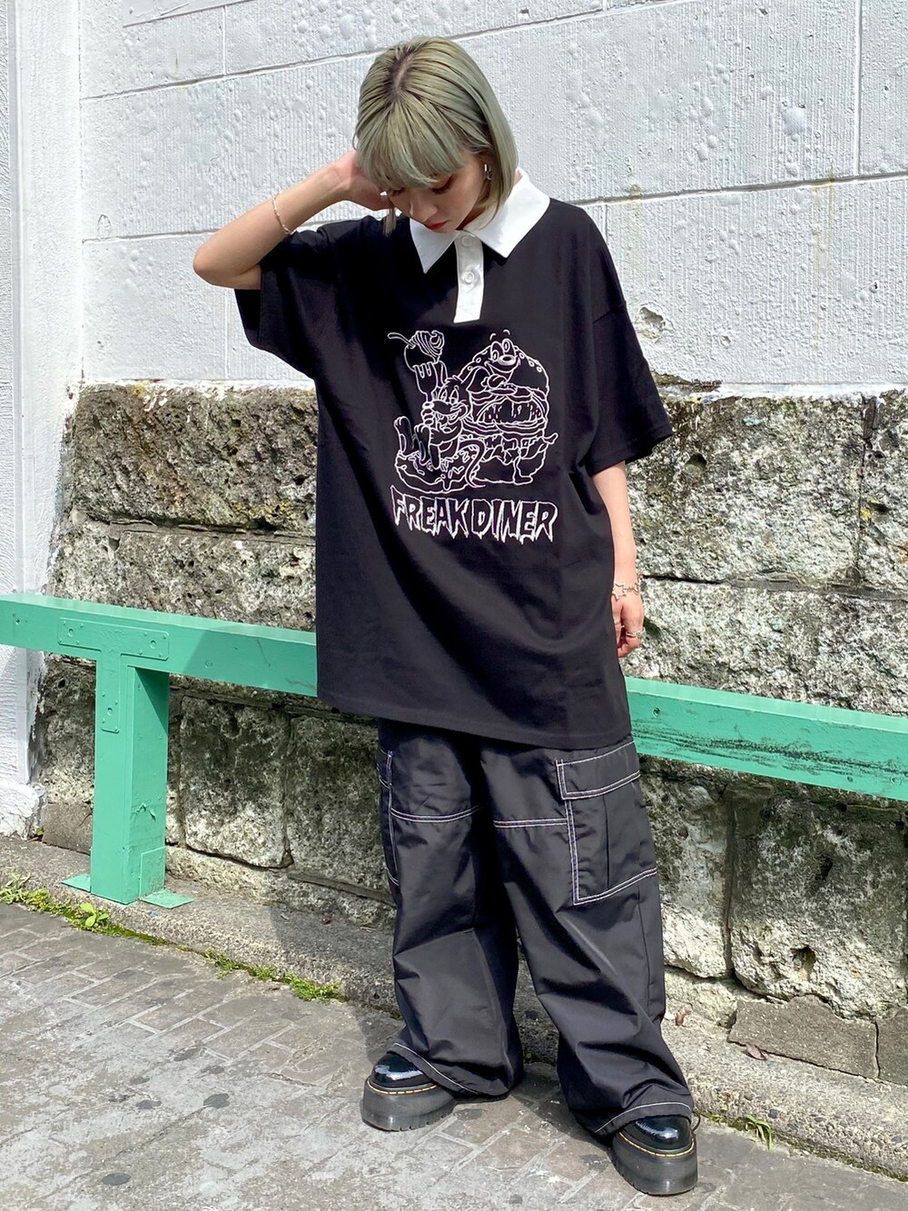 ブラック系のポロシャツ、ブラック系のシューズ、ブラック系のカーゴパンツを着用したレディースの春コーディネートの2枚目の写真