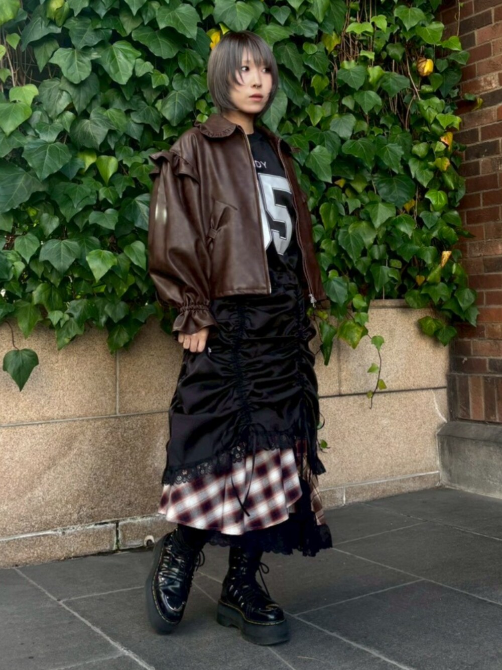 ブラウン系のライダースジャケット、ブラック系のワンピース、レッド系のスカートを着用したレディースの冬コーディネートの2枚目の写真